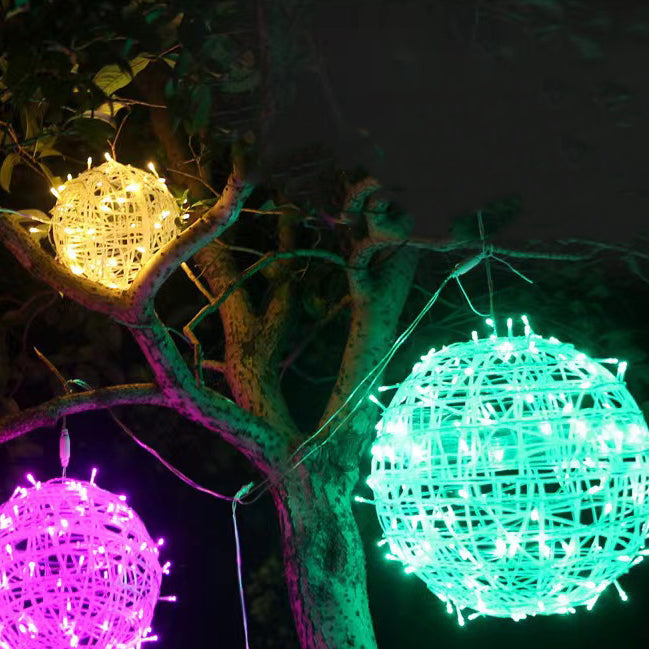 Warm white, pink and green LED ball lights hanging in a tree at night