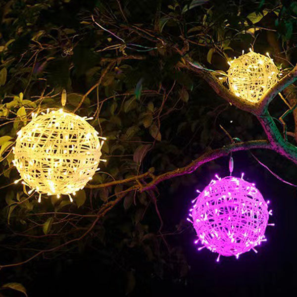 Two warm white LED ball lights and one purple ball light hanging in a leafy tree at night