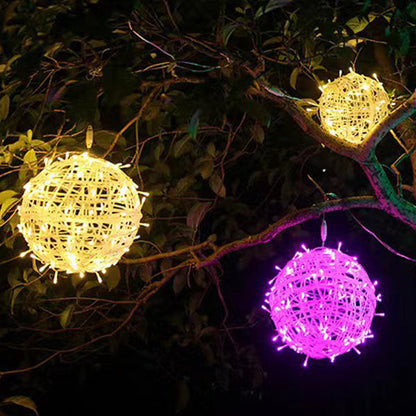 Two warm white LED ball lights and one purple ball light hanging in a leafy tree at night