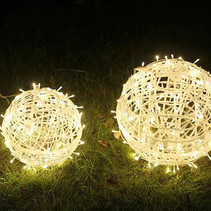Two warm white LED ball lights of different sizes sitting on a lawn at night