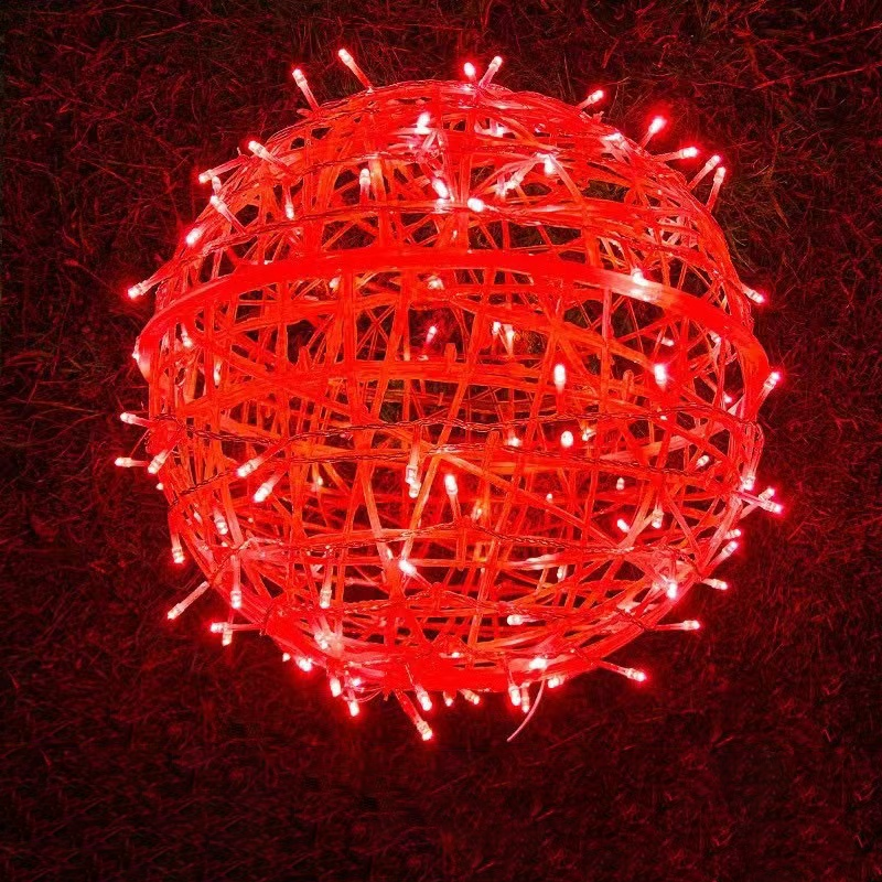 A red LED ball light resting on grass at night
