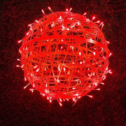 A red LED ball light resting on grass at night