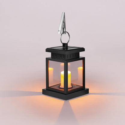 Solar candle lantern glowing warm amber through four clear panels, with a metal hanging clip on top