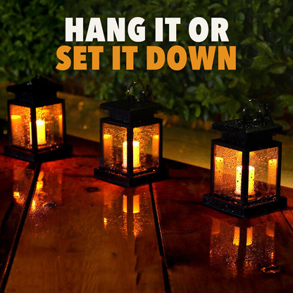 Three solar candle lanterns glowing on a wet wooden deck, with the words hang it or set it down