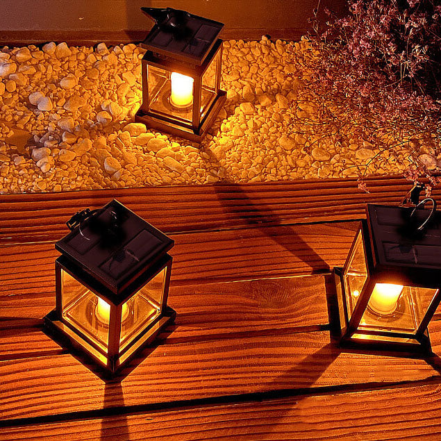 Solar candle lanterns glowing on deck boards and white gravel, seen from above with the solar cells on their roofs