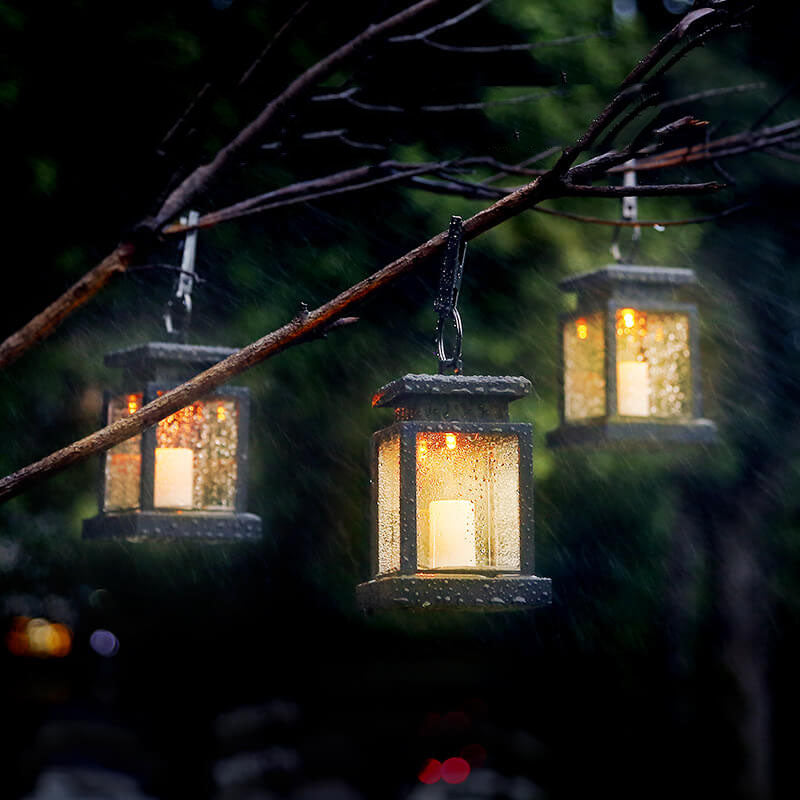 Solar candle lanterns glowing in a tree during heavy rain at night