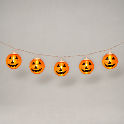 Five lit orange jack-o'-lantern lanterns hanging from clear wire in a gentle swag on a grey background