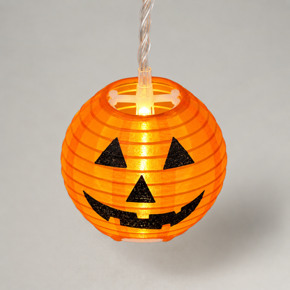 One lit orange ribbed lantern with a black jack-o'-lantern face, seen from slightly above to show the white spreader and LED in its open top