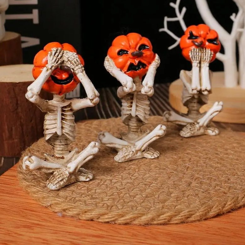 Pumpkin head skeleton figurines in see no evil, hear no evil and speak no evil poses on a round jute mat
