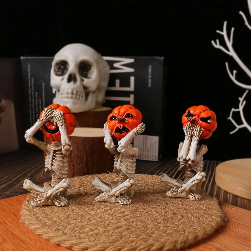 Three pumpkin head skeleton figurines in see, hear and speak no evil poses on a jute mat