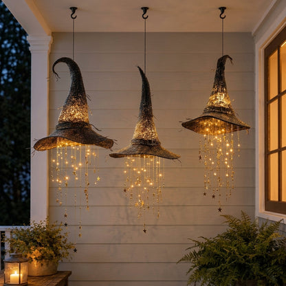 Three dark woven witch hat lights hanging from a porch ceiling at dusk, warm LED star strands falling from each brim