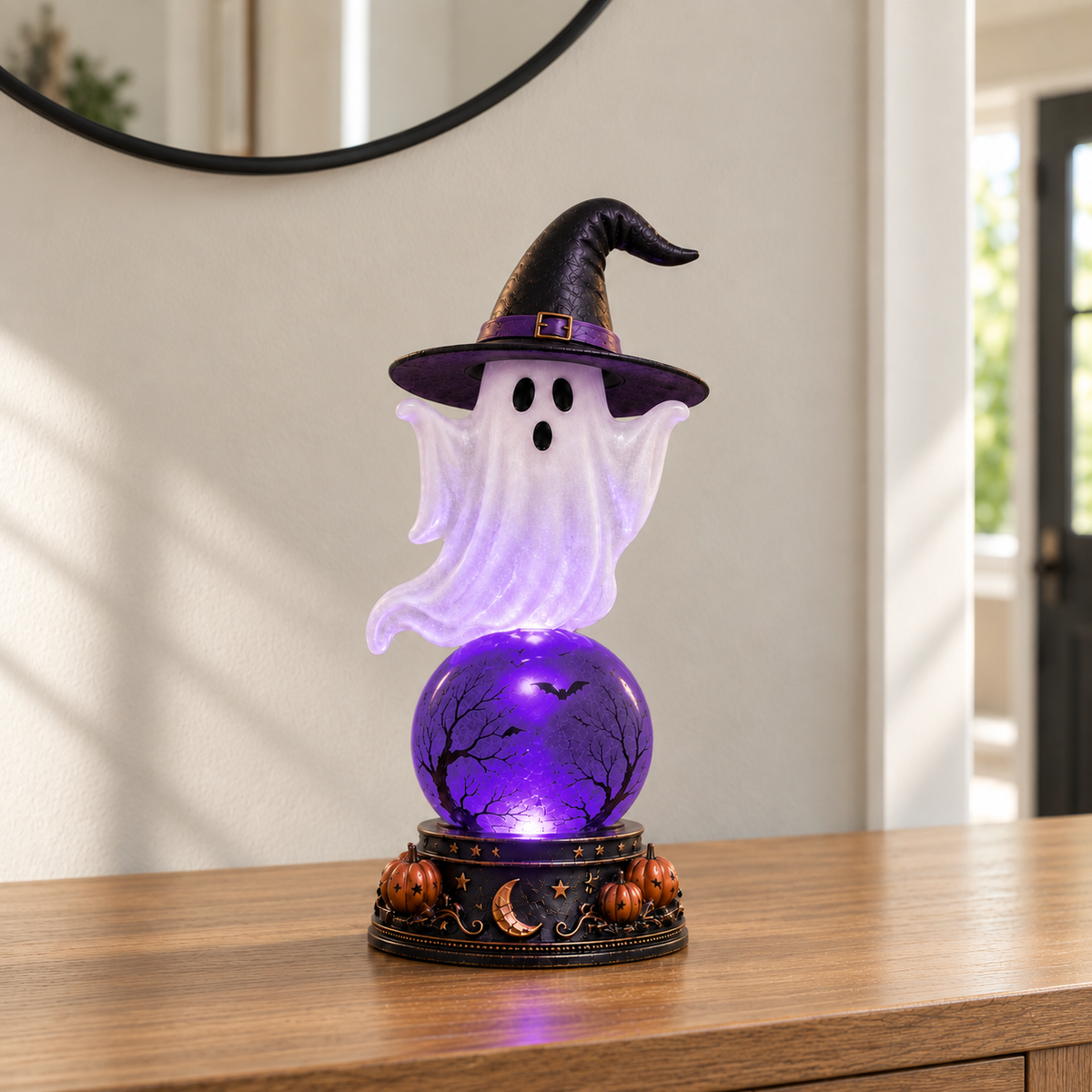 Crystal ball lamp with a frosted ghost in a witch hat over a glowing purple orb, on a hall console