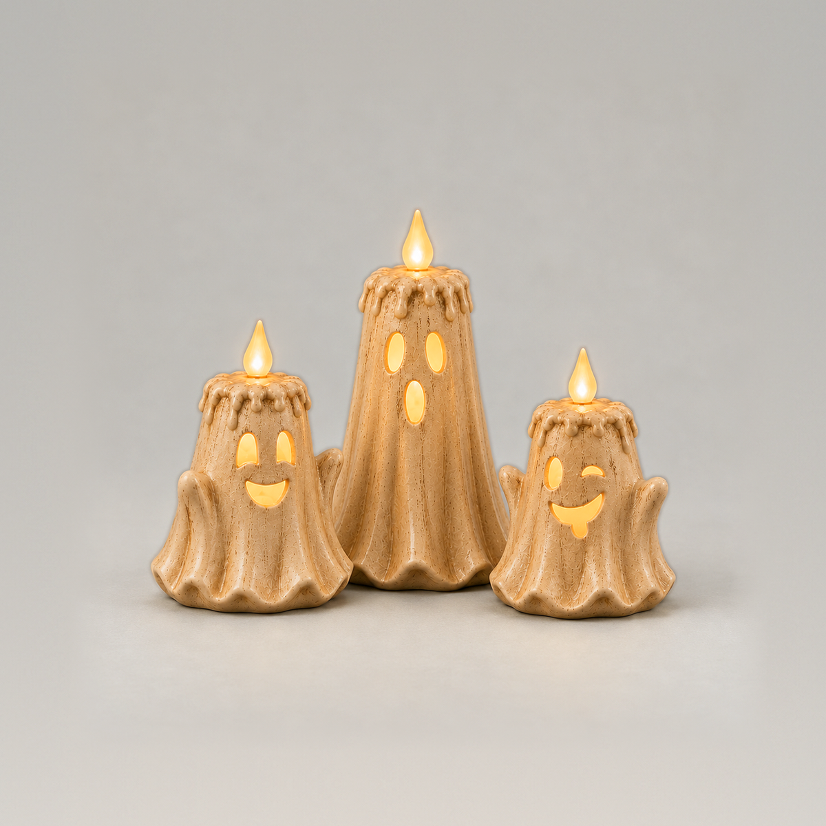 Set of three ghost LED candles, surprised, grinning and winking faces glowing, on a plain grey background
