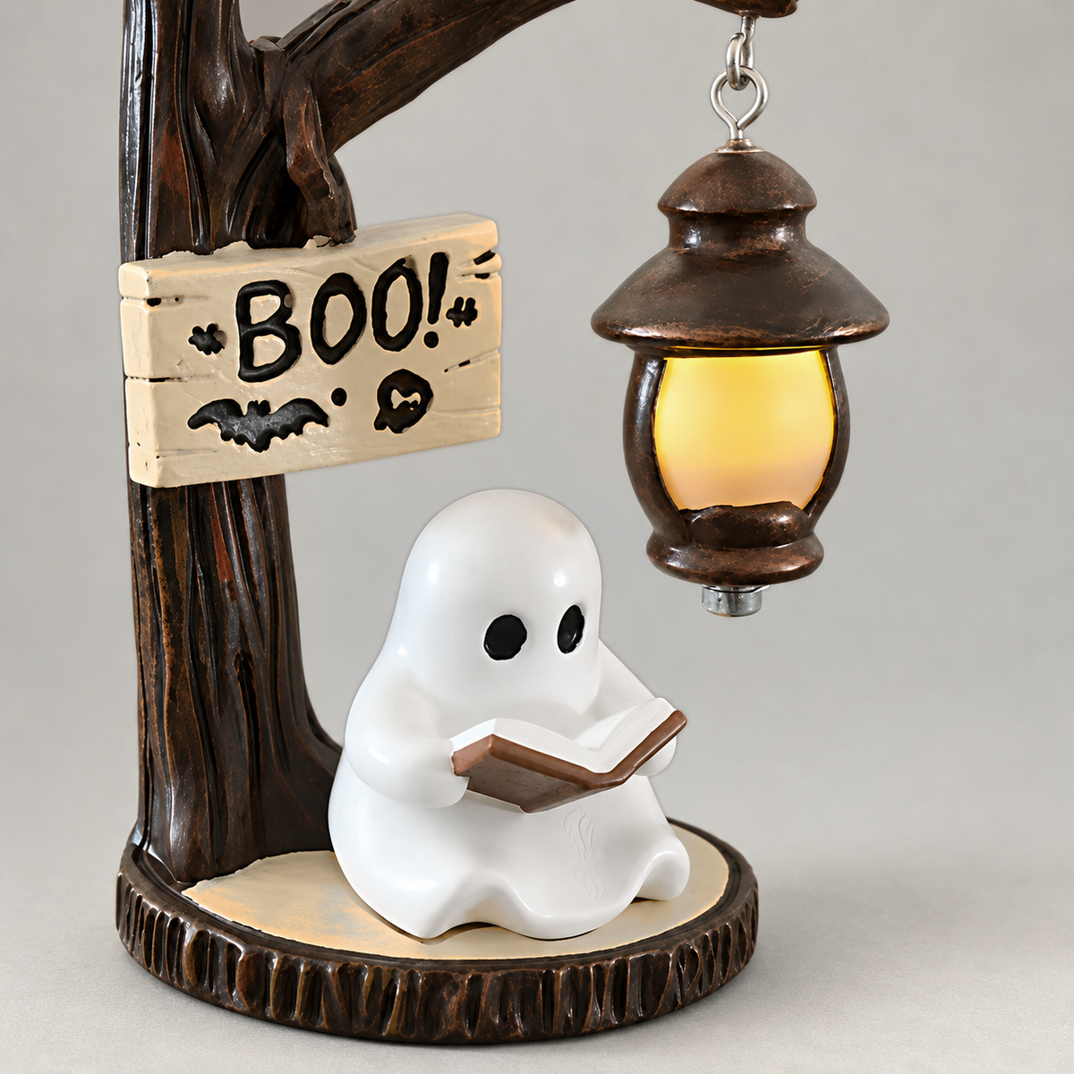 Close view of the white ghost holding its open book under the small lit lantern, on a grey background