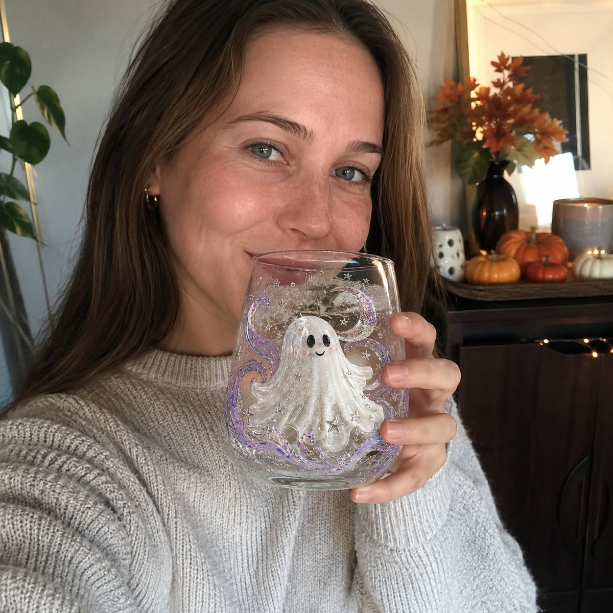 A woman holding a Halloween drinking glass with a raised white ghost design