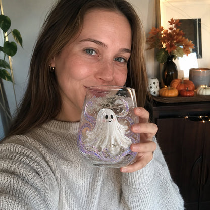 A woman holding a Halloween drinking glass with a raised white ghost design