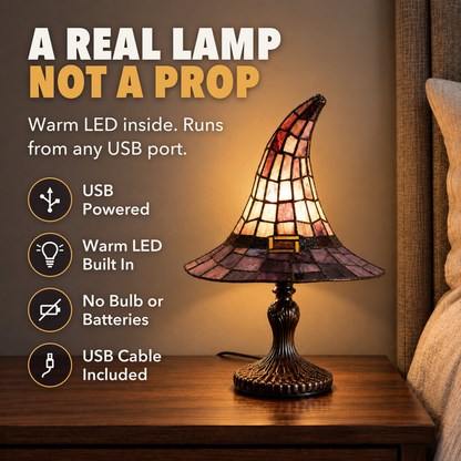 Witch hat table lamp glowing on a nightstand, with the words A real lamp, not a prop, USB powered, warm LED built in, no bulb or batteries, USB cable included