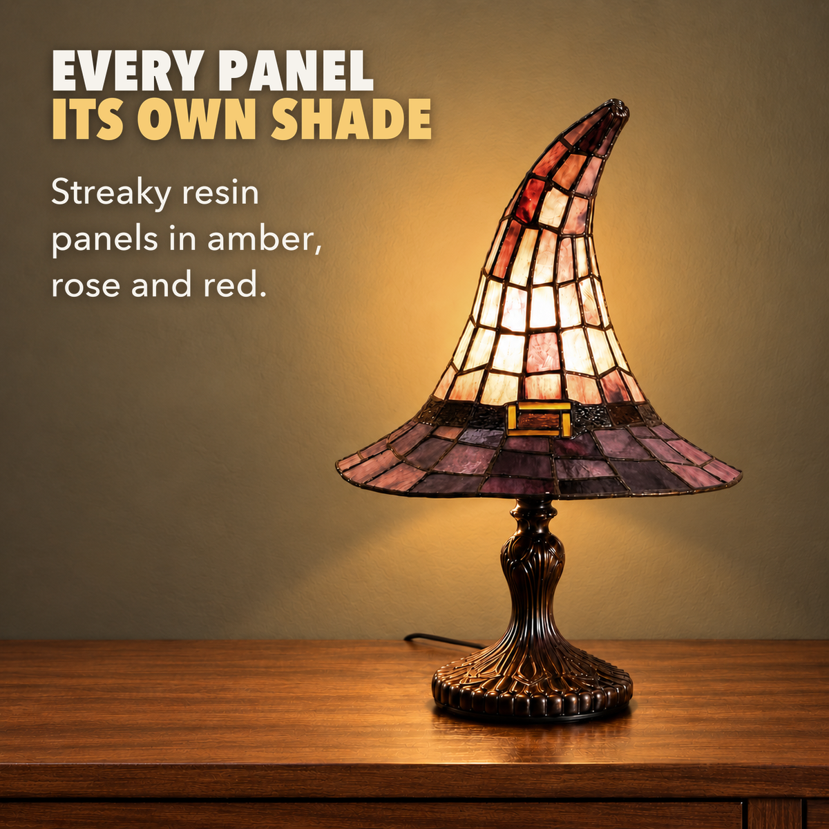 Close view of the witch hat lamp's streaky amber, rose and red panels glowing, with the words Every panel its own shade