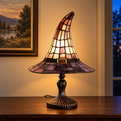 Large witch hat table lamp lit on a dining room sideboard in the evening, below a framed landscape painting