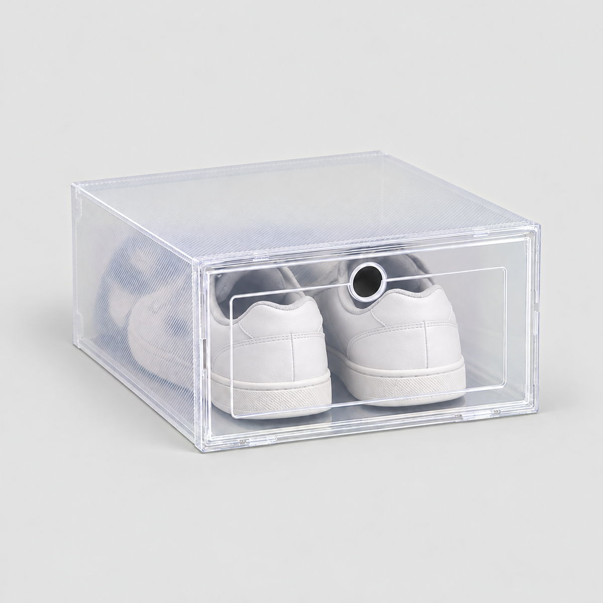 One clear shoe box with a drop front door holding white sneakers, on a plain light grey background