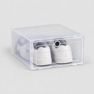 One clear shoe box with a drop front door holding white sneakers, on a plain light grey background