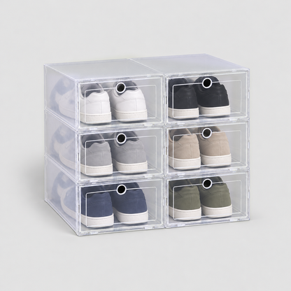Set of six clear shoe boxes stacked two across and three high, a pair of sneakers in each, on a plain light grey background