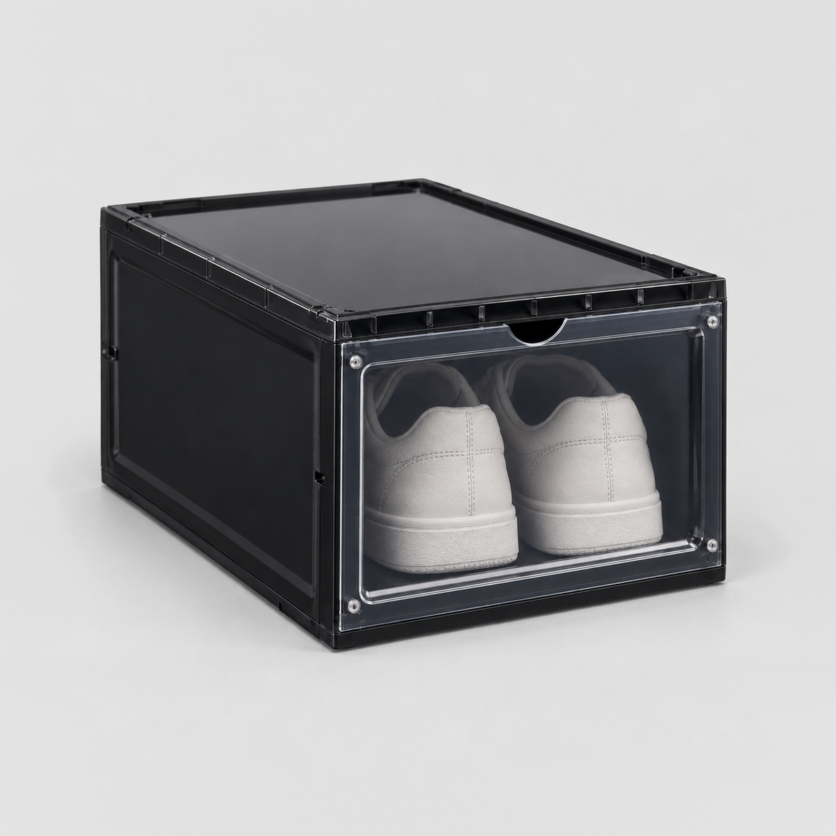 Black drop front shoe box with a see-through door and white sneakers inside, on a plain light grey background