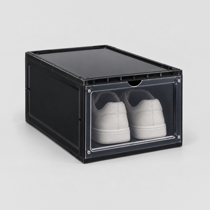 Black drop front shoe box with a see-through door and white sneakers inside, on a plain light grey background