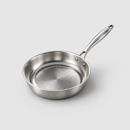 Hammered frying pan with a honeycomb interior and a riveted metal handle on a light grey background