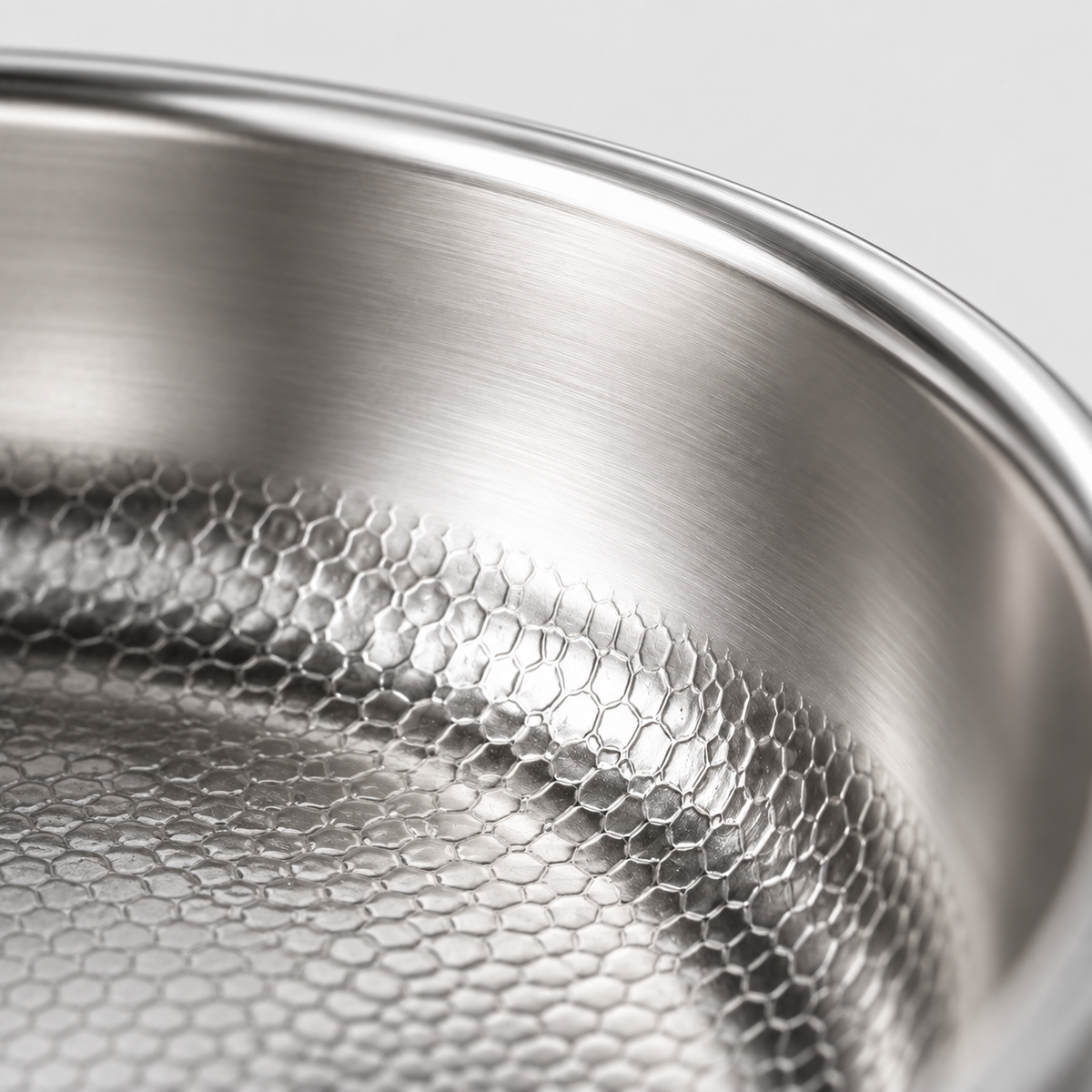 Close-up of the raised honeycomb hammered surface meeting the brushed wall and rolled rim