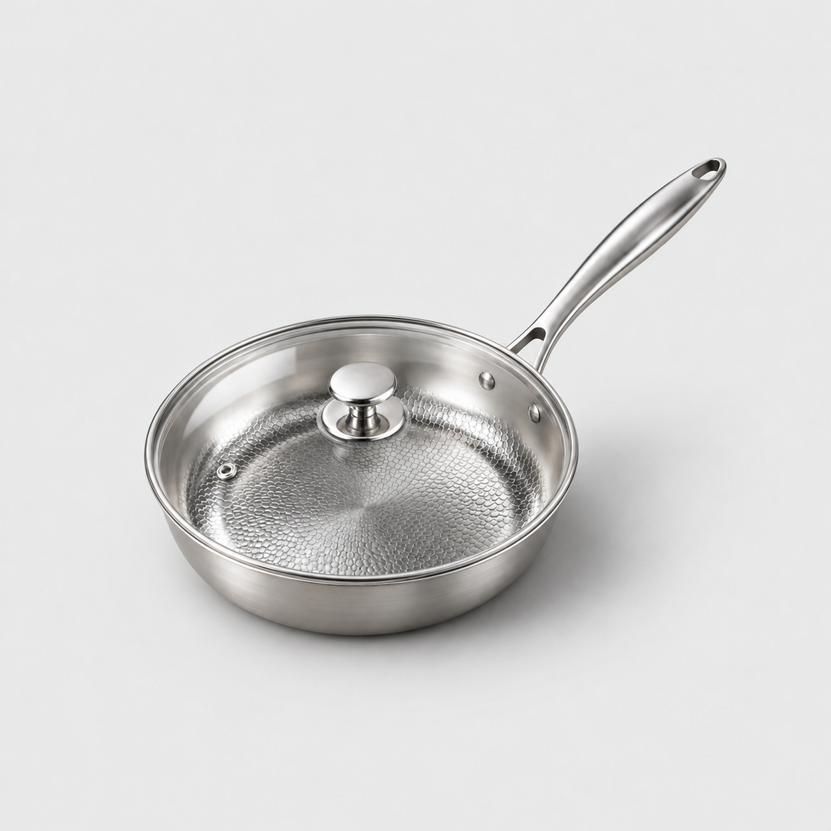 Hammered frying pan with its clear glass lid on, showing the metal rim band, round knob and one steam vent