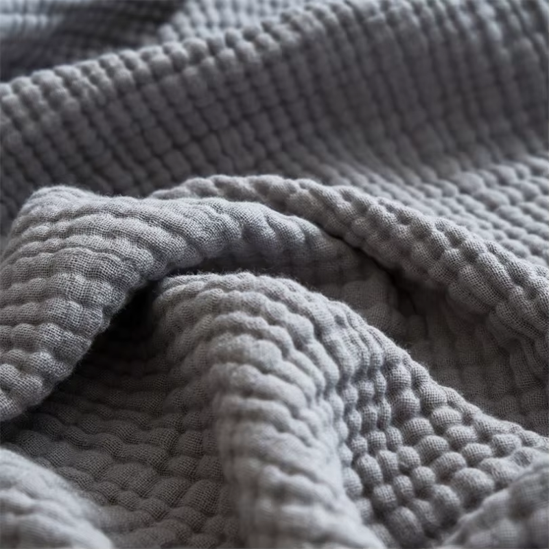 A close view of gray crinkled cotton gauze lying in soft, rounded folds.