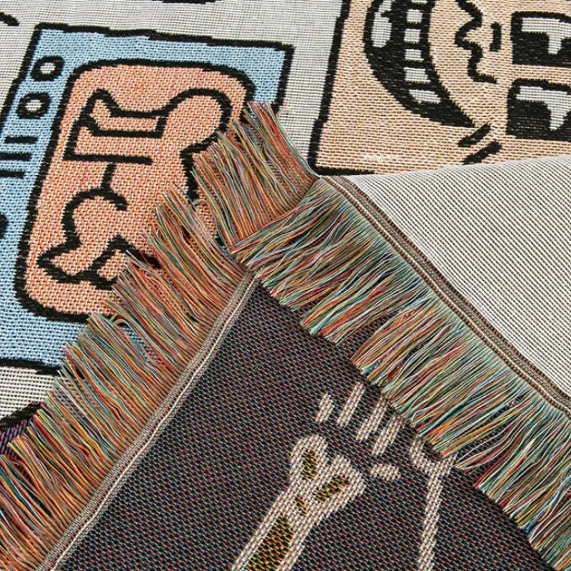 A corner of the throw folded back to show the darker flecked reverse and a cream figure, with a multicolored fringe.
