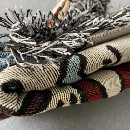 Folded layers of the throw seen side-on, with the loose fringe along the top.
