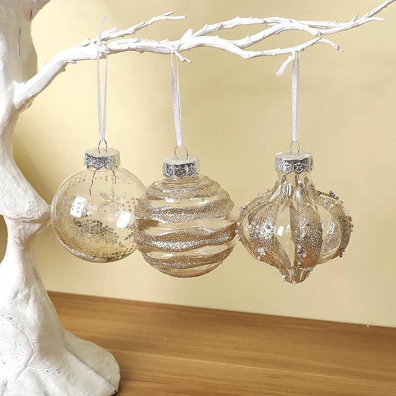 Three champagne baubles hanging from a white branch: sequin, swirl and droplet designs with silver caps