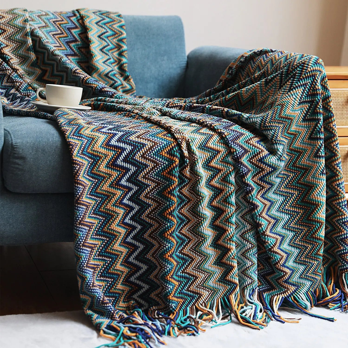 A blue chevron throw with teal, navy and mustard zigzags spread across a blue couch.
