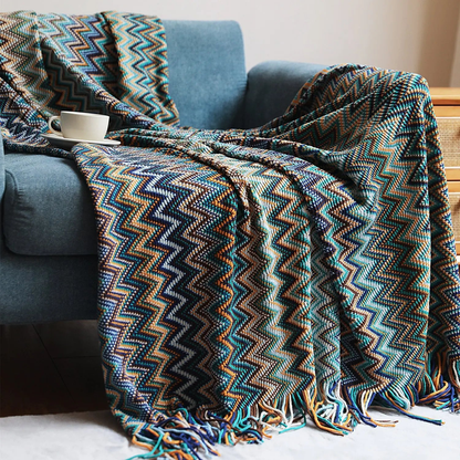 A blue chevron throw with teal, navy and mustard zigzags spread across a blue couch.