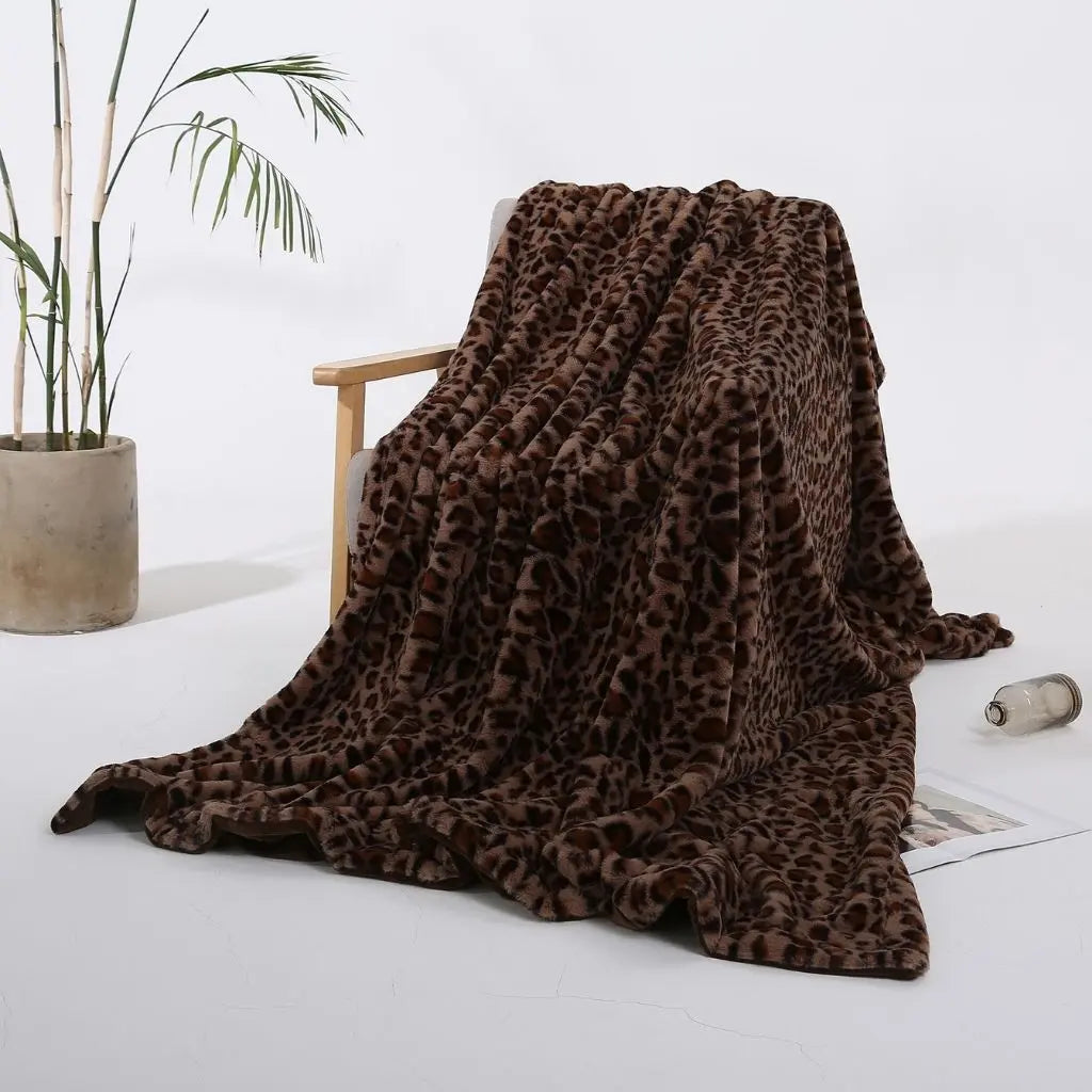 A brown leopard print throw blanket with near-black spots on a deep brown ground, draped over a wooden armchair.