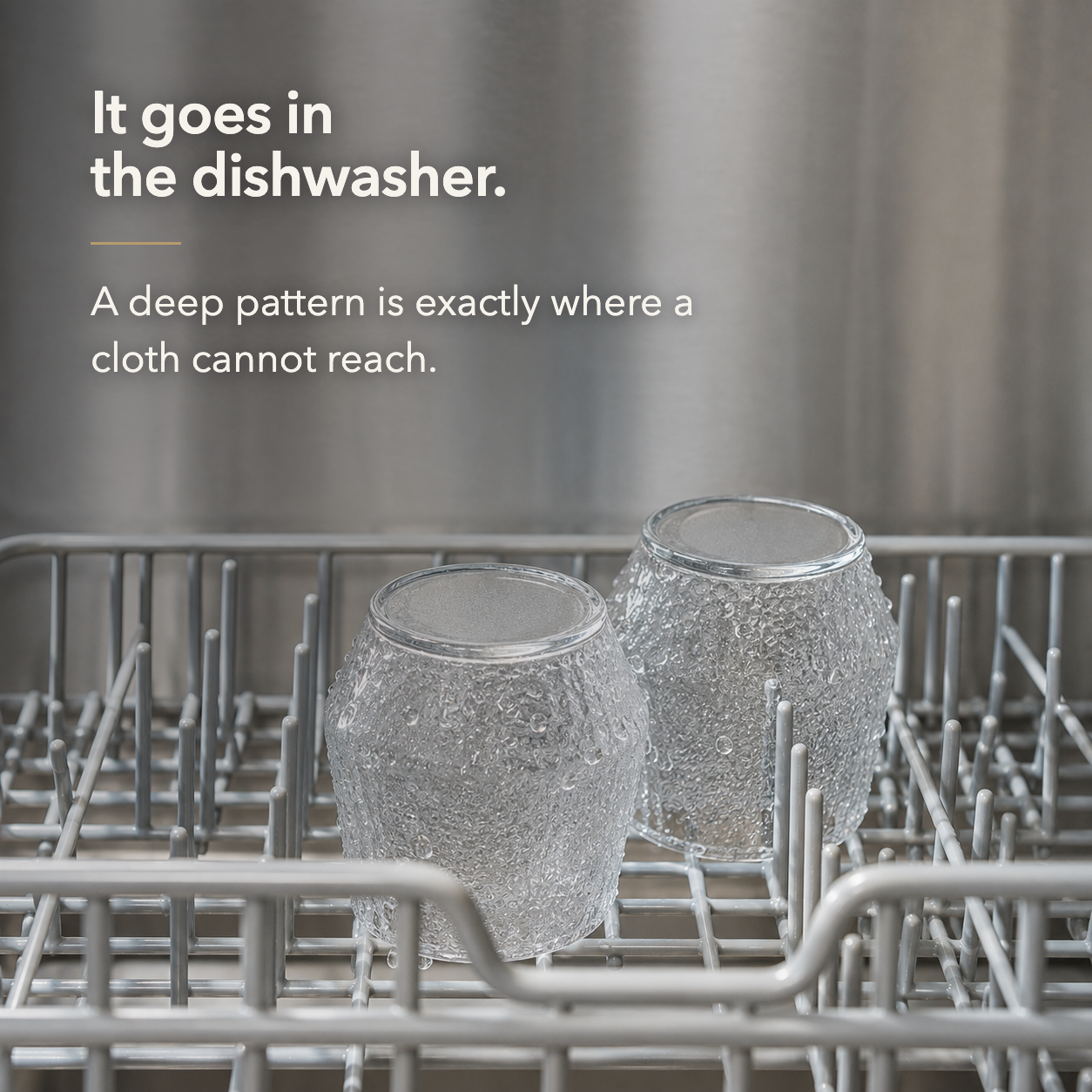 Two hammered whiskey tumblers standing upside down on a dishwasher rack after a wash
