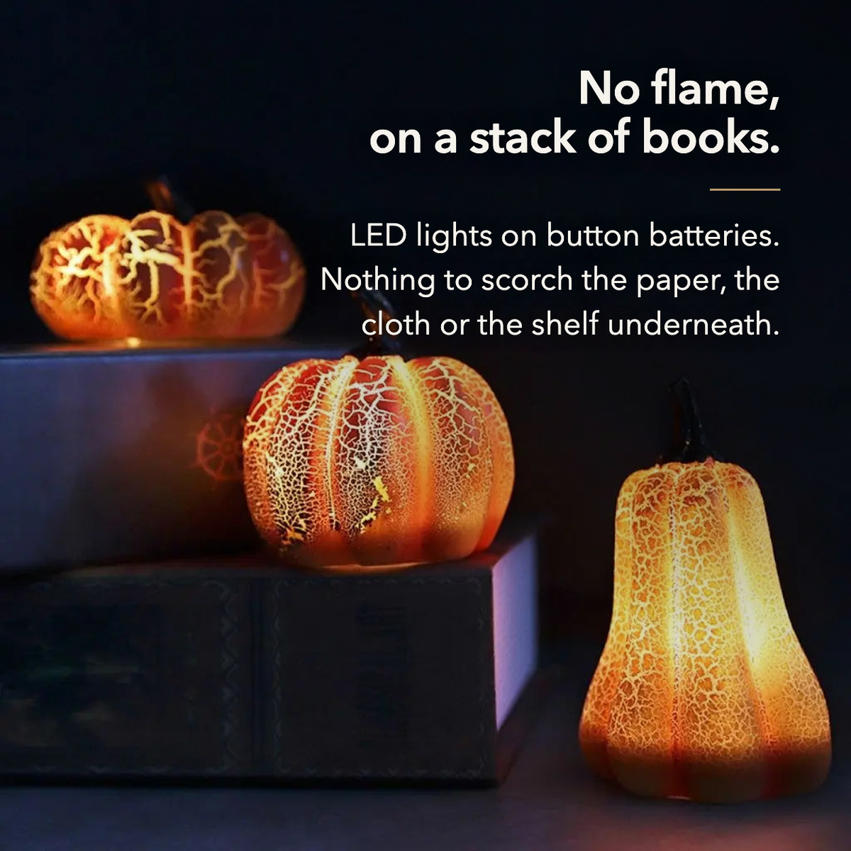 A lit resin pumpkin light standing on a stack of books in the dark