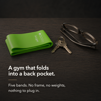 A loop resistance band folded flat on a desk beside a set of keys and a pair of folded glasses