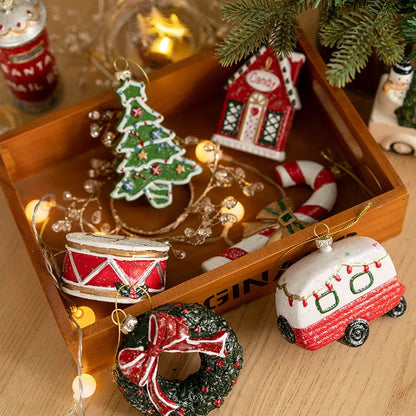 Tree, house, drum, wreath and camper trailer Christmas ornaments seen from above in a wooden tray with fairy lights