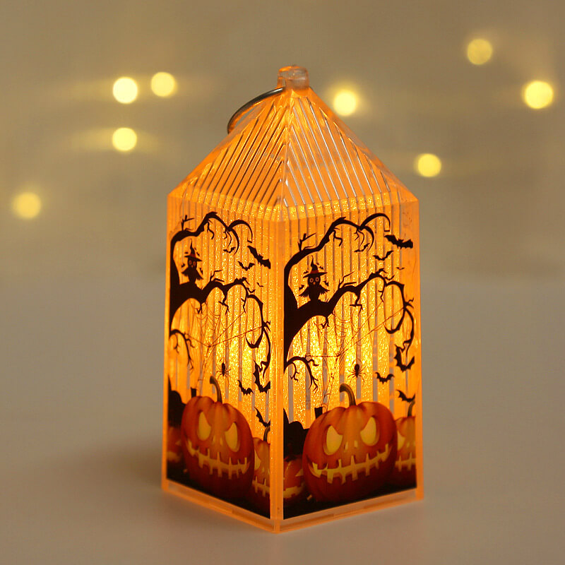 Mini Halloween lantern lit warm amber, printed with carved jack-o'-lanterns beneath bare trees and a spider web