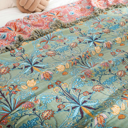 Close view of the bedspread folded back at the head of the bed, showing the coral reverse and the fringe