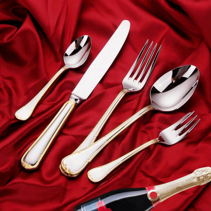 Five-piece gold trim flatware setting on red satin with a bottle of sparkling wine