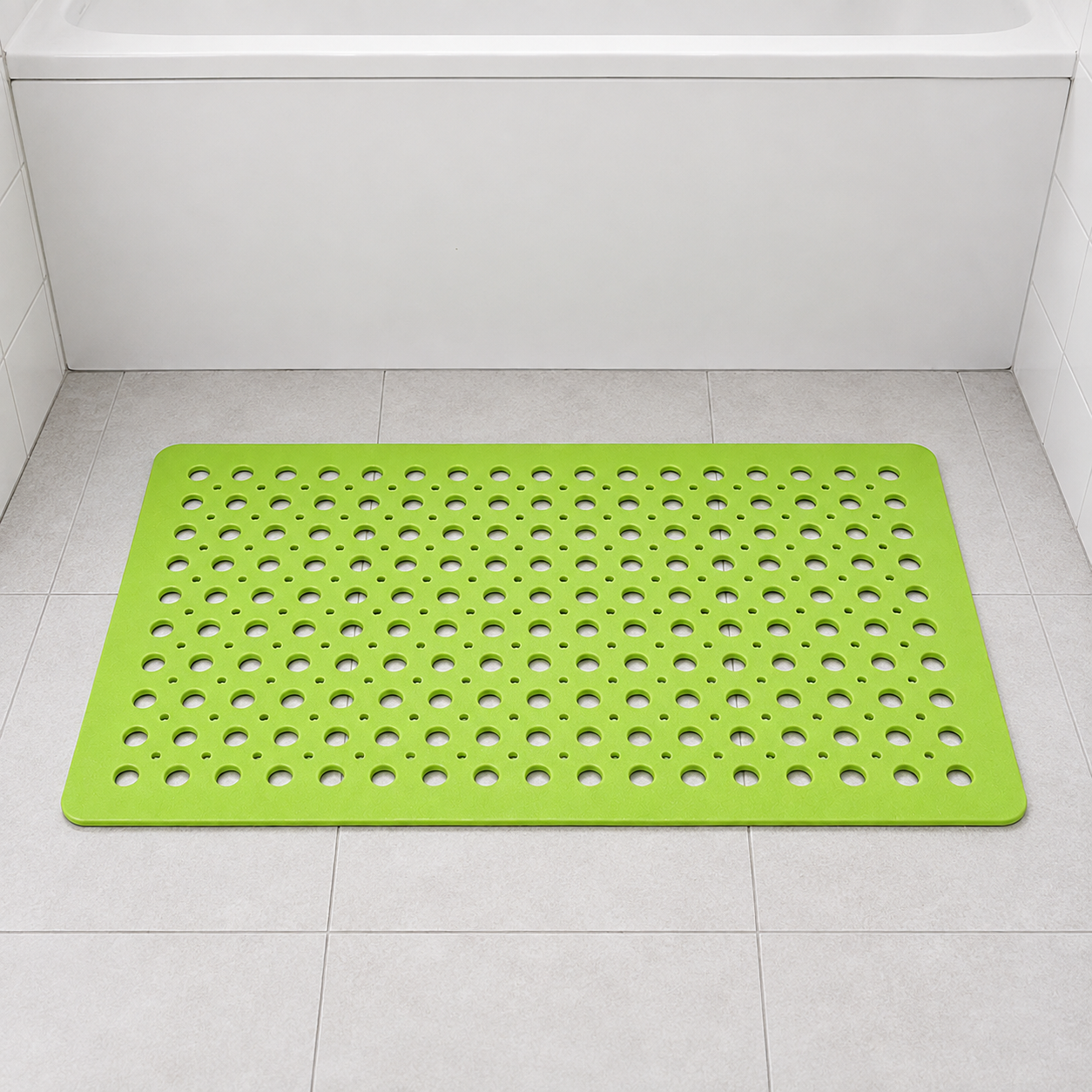 Green non slip shower mat with drainage holes on a pale tiled floor in a family bathroom