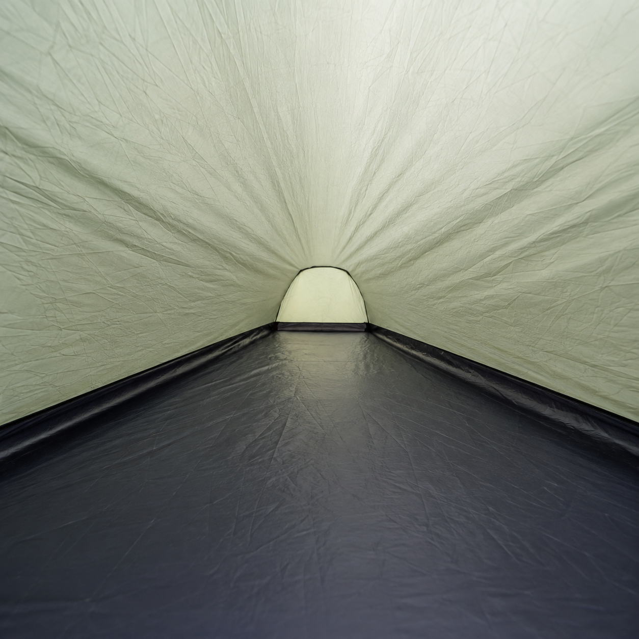 Inside the one-person tent looking down its length to the lit door, showing the coated floor