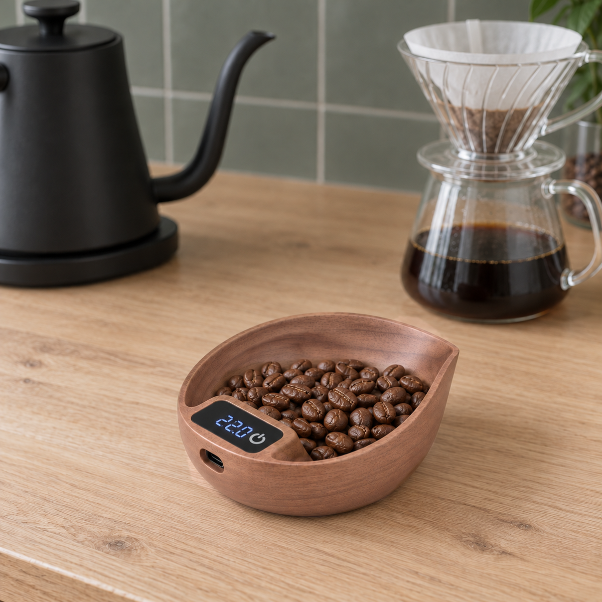Walnut coffee scale with a dose of beans beside a glass pour-over dripper and a gooseneck kettle on an oak counter