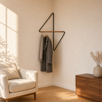 Wider view of a living room corner in late daylight, with the black metal corner coat rack holding a coat and a scarf on hangers.