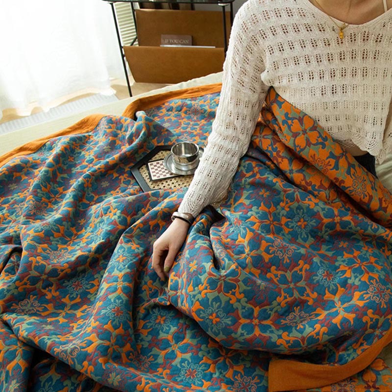The blue and orange quilt pulled over the lap of someone sitting up in bed